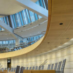 Acoustic lightboard με καμπύλες ξύλινες επιφάνειες και ενσωματωμένο φωτισμό σε σύγχρονο εσωτερικό χώρο